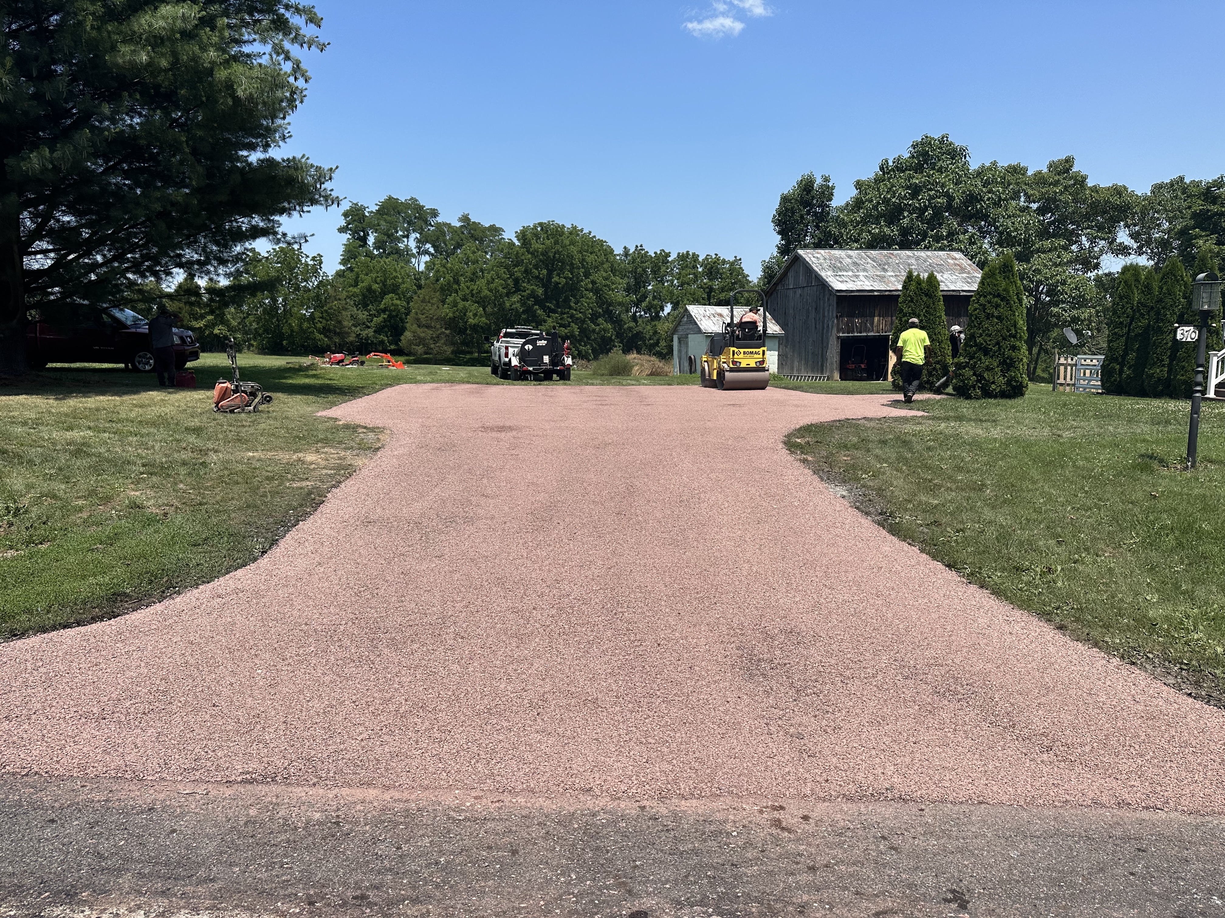 Fresh chip seal driveway surface with paving equipment nearby